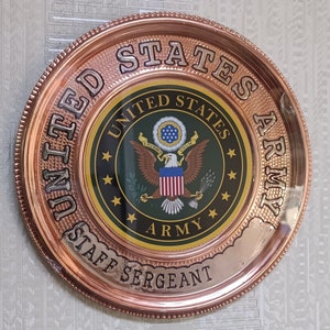 May include: A copper-colored round plaque with the words "United States Army Staff Sergeant" around the edge. The center of the plaque features the United States Army seal with an eagle and the words "United States Army".