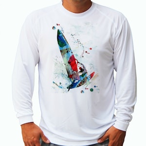 Puede incluir: Camiseta blanca de manga larga con un diseño de acuarela colorido de una persona haciendo windsurf. El diseño presenta salpicaduras de pintura azul, roja, verde y amarilla.