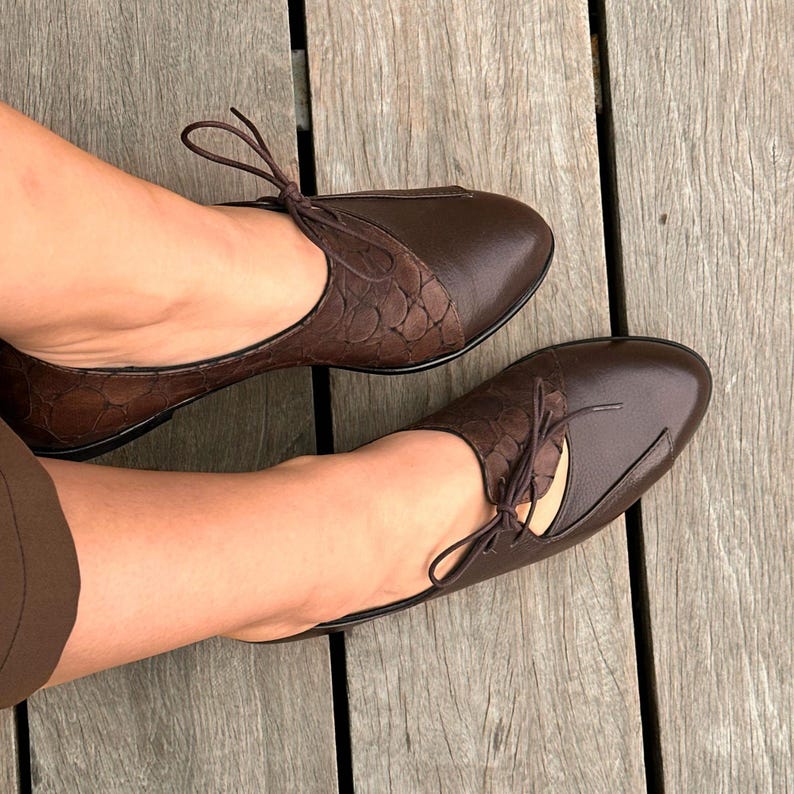 May include: A pair of brown leather shoes with a lace-up design. The shoes have a textured pattern and a pointed toe.