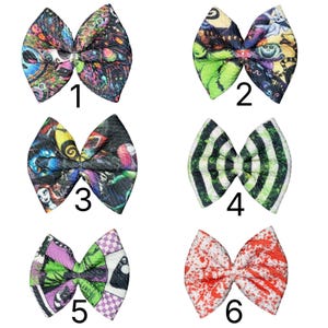 May include: Six colorful fabric hair bows with various patterns. Designs include a black and green pattern, a black and white striped pattern, and a red and white splatter pattern. Each bow is numbered 1 through 6.