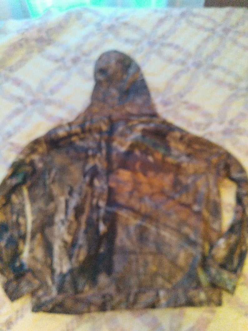 May include: Camouflage hooded sweatshirt with a brown, green and black pattern.