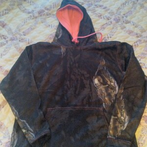 May include: A black and brown camouflage hoodie with a pink lining and a drawstring hood.