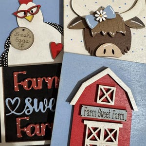 May include: A collection of wooden farm-themed decorations. Includes a chicken wearing glasses with a "Fresh Eggs" sign, a cow with a blue bow, a barn with "Farm Sweet Farm" text, and a sign that says "Farm Sweet Farm".