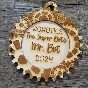 May include: A wooden ornament with a gear pattern and the text "Robotics The Super Bots Mr. Bot 2024".