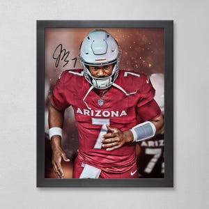 May include: Framed print featuring an athlete in a red football uniform with the word "ARIZONA" and the number "7" visible. The athlete is wearing a helmet and wristbands. The image is signed in black ink.