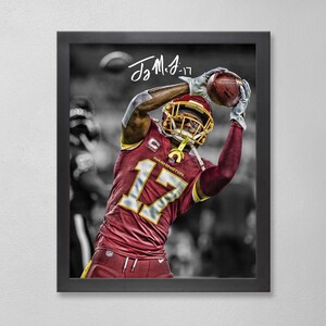 May include: Framed print featuring a football player in a burgundy and gold uniform, catching a football. The player wears a helmet with the number 17. The background is in black and white.