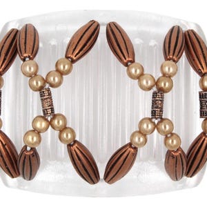May include: A decorative hair comb featuring a clear base with a series of teeth. The comb is adorned with bronze-colored, oval-shaped beads with vertical lines, interspersed with faux pearl beads. The design includes decorative cylindrical accents.