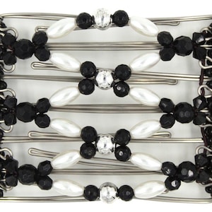 May include: A hair comb featuring a silver-toned metal frame with elastic cords. The design includes white oval beads, faceted black beads, and clear crystal-like accents arranged in a repeating pattern, with solid black beaded edges on both sides.