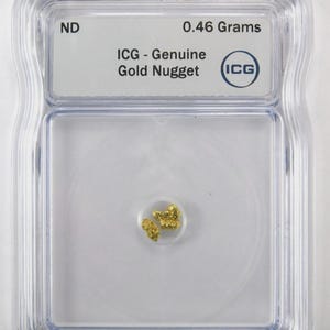 Könnte beinhalten: Ein kleiner, echter Goldnugget mit einem Gewicht von 0,46 Gramm, eingeschlossen in einer durchsichtigen, rechteckigen ICG-Schutzhülle aus Kunststoff. Das Etikett im Inneren zeigt den Text ND, 0.46 Grams, ICG - Genuine Gold Nugget und das ICG-Logo.