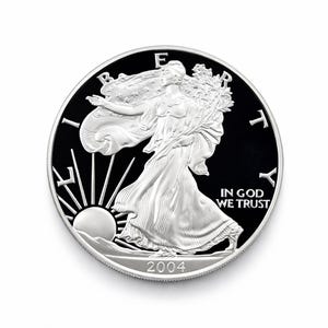 May include: A silver coin with a black background featuring a woman in a flowing gown, holding a branch and walking towards the sun. The coin has the text "LIBERTY", "IN GOD WE TRUST", and the year "2004".