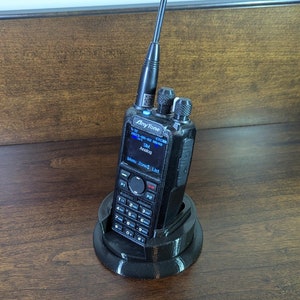 May include: A black two-way radio with an antenna, a screen displaying "AnyTone AT-D878UV", and a black charging base.