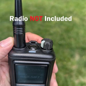 Peut inclure: Un bouton de volume de remplacement noir texturé avec une bande indicatrice blanche pour une radio bidirectionnelle portable. Le bouton présente une prise striée et est fixé sur une radio noire avec antenne. Le texte Radio NOT Included est visible.