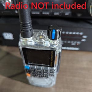May include: A clear, handheld radio with a black antenna and a black knob with a blue stripe. The radio has a small screen and a keypad. The text "Radio NOT included" is visible in the background.
