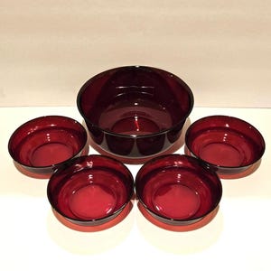 Puede incluir: Un juego de cinco cuencos de vidrio rojo, que incluye un cuenco grande para servir y cuatro cuencos más pequeños. Los cuencos están hechos de vidrio transparente con un tono rojo intenso.