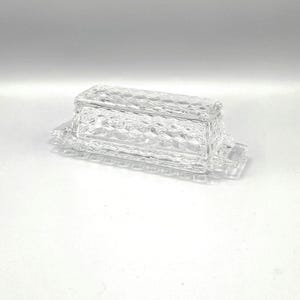 May include: A clear glass butter dish with a lid. The dish has a diamond pattern.