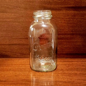 May include: A clear glass canning jar with the word "Kerr" and "Mason" embossed on the side.
