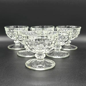 May include: Set of six clear glass dessert dishes with a textured, diamond-shaped pattern. The dishes have a footed base.