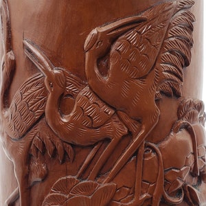 Könnte beinhalten: Eine braune Holzvase mit einem geschnitzten Design aus Kranichen und Blumen. Die Vase ist aufwendig verziert und hat einen rustikalen Look.