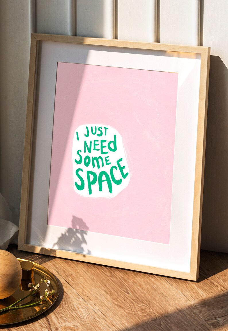 Op de afbeelding: Een ingelijst print met een roze achtergrond en witte tekst die "Ik heb gewoon wat ruimte nodig" in groene letters zegt.