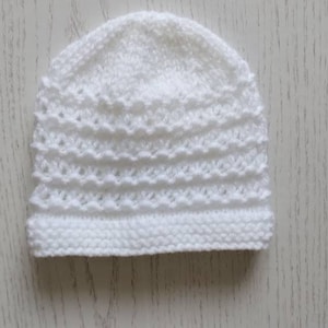 May include: A white crocheted baby hat with a delicate stitch pattern.