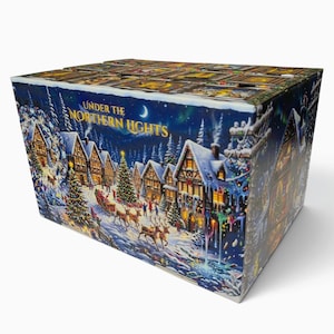 May include: A rectangular cardboard box featuring a winter village scene with the text Under the Northern Lights. The illustration depicts snow-covered houses, decorated Christmas trees, a horse-drawn sleigh, and reindeer under a night sky.