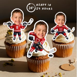 Puede incluir: Tres cupcakes cubiertos con imágenes de dibujos animados de un niño con uniforme de hockey. El niño lleva una camiseta roja con el número 8. Los cupcakes tienen glaseado blanco y están decorados con pistachos. El texto dice "READY IN 24 HOURS."