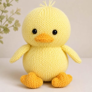 May include: A knitted yellow duck toy with a round body, small wings, and orange feet and beak. The duck has black bead eyes and a small tuft of yellow yarn on its head. Text at the top reads Aran ( 10ply, Medium Worsted 4 ) and at the bottom Knittropolis.etsy.com.
