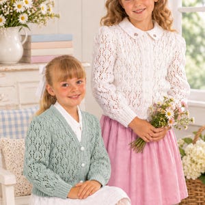 May include: A white long-sleeve knit cardigan with a collar and a light green long-sleeve knit cardigan with a V-neck. Both cardigans feature an intricate openwork pattern, ribbed cuffs, and round buttons down the front centre.