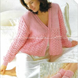 Könnte beinhalten: Hellrosa Strickjacke mit V-Ausschnitt und Knopfverschluss. Die Ärmel haben ein strukturiertes Zickzackmuster. Das Bild zeigt auch ein Paar passende Stricksocken mit gerolltem Bündchen. Der Text "INCLUDES LARGER SIZES" ist sichtbar.