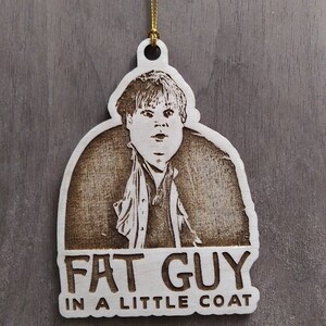 Puede incluir: Un adorno navideño de madera con una imagen grabada con láser de un hombre con abrigo y el texto "FAT GUY IN A LITTLE COAT".