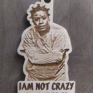 May include: A wooden ornament featuring a laser-engraved image of a person with the text "I AM NOT CRAZY I AM UNIQUE".