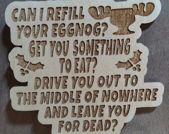 May include: A wooden Christmas ornament with the text "CAN I REFILL YOUR EGGNOG? GET YOU SOMETHING TO EAT? DRIVE YOU OUT TO THE MIDDLE OF NOWHERE AND LEAVE YOU FOR DEAD?"