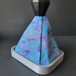 May include: A gray 3D printed base with a purple and teal paisley patterned fabric gear shift knob with a black diamond-shaped top.