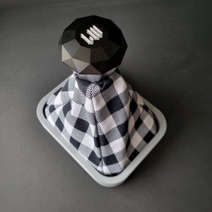 May include: Black and white checkered gear shift boot with a black diamond-shaped gear knob with a silver "III" logo.