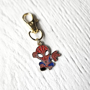 May include: Gold-coloured keychain with a small, red and blue cartoon Spider-Man figure attached.