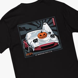 May include: A black t-shirt with a graphic of a red car with a pumpkin on the hood and a ghost behind it. The graphic is in a Japanese style with a red sunburst background. The text "The Wandering Daisy & Co." and "デージー" are below the graphic.