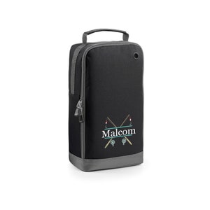 Puede incluir: Bolsa de zapatos negra con cierre de cremallera y asa gris. La bolsa tiene un dise&ntilde;o de ca&ntilde;a de pescar con el nombre "Malcolm" bordado.