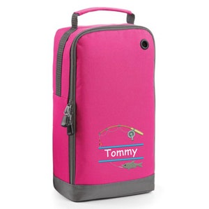May include: Pink shoe bag with a zipper closure and a gray bottom. It features a fishing rod and fish design with the name "Tommy" embroidered on it.