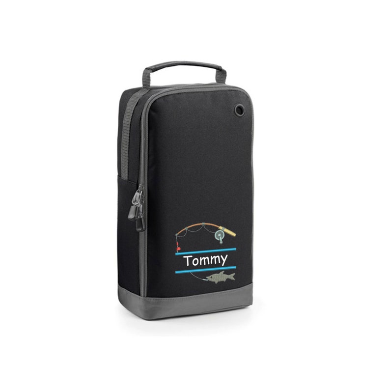 May include: Black zippered duffel bag with a gray trim. The bag has a fishing rod, reel, and fish embroidered on the front. The name "Tommy" is embroidered below the fishing rod.
