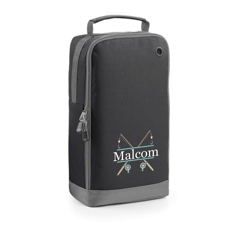 Puede incluir: Bolsa para zapatos negra y gris con cierre de cremallera y asa. La bolsa tiene un dise&ntilde;o de dos ca&ntilde;as de pescar cruzadas con un carrete de pesca y un flotador rojo en cada ca&ntilde;a. El nombre "Malcolm" est&aacute; impreso en letras blancas debajo de las ca&ntilde;as de pescar.