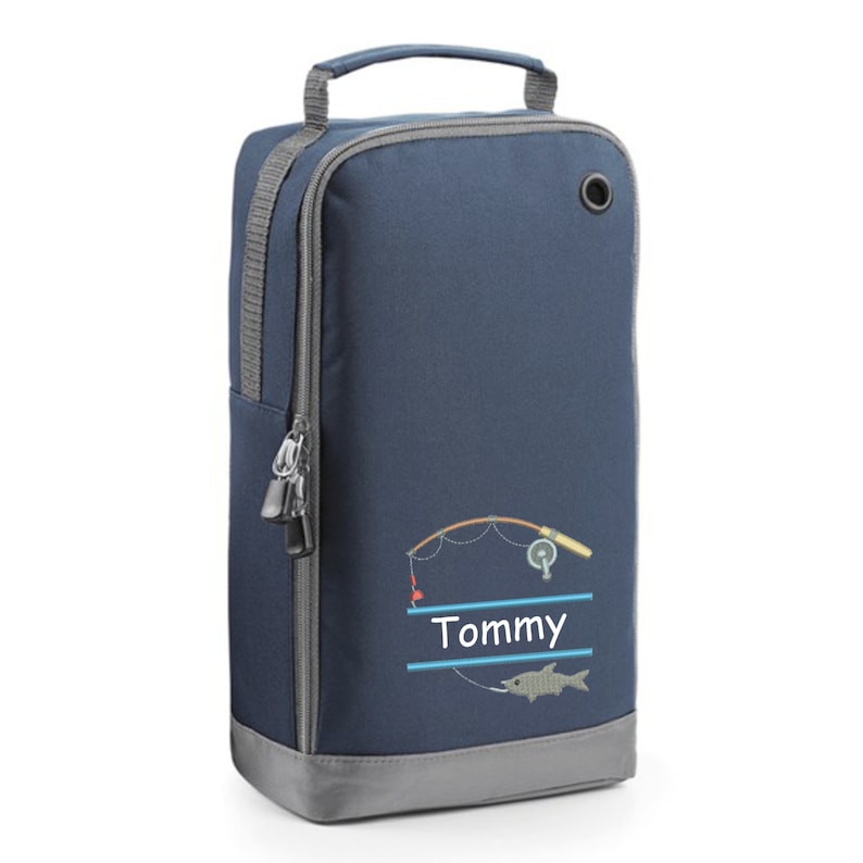 May include: A navy blue shoe bag with a zipper closure and a gray handle. The bag has a fishing rod and fish design with the name "Tommy" embroidered on it.