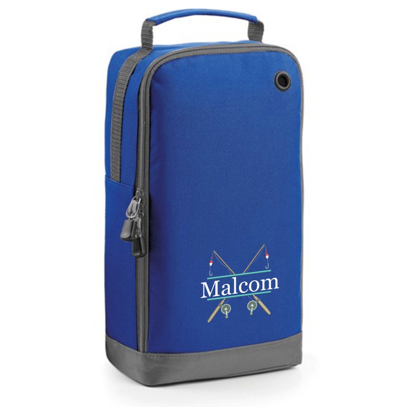 Puede incluir: Bolsa de deporte azul y gris con cierre de cremallera y asa. La bolsa tiene un dise&ntilde;o de dos ca&ntilde;as de pescar cruzadas con un anzuelo y un flotador en cada ca&ntilde;a. El nombre "Malcolm" est&aacute; impreso en letras blancas sobre una pancarta azul entre las ca&ntilde;as.
