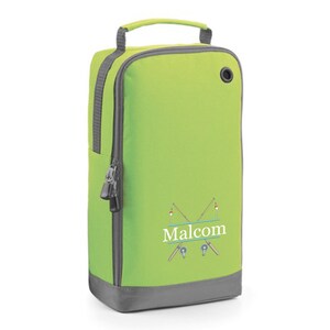 Puede incluir: Una bolsa para zapatos de color verde lima con una cremallera gris y una base gris. La bolsa tiene un asa en la parte superior y un peque&ntilde;o agujero en el lateral. La bolsa tiene un dise&ntilde;o de dos ca&ntilde;as de pescar cruzadas con un flotador rojo en cada ca&ntilde;a. El texto "Malcolm" est&aacute; impreso en blanco sobre una pancarta verde entre las ca&ntilde;as de pescar.