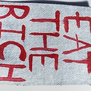 K&ouml;nnte beinhalten: Nahaufnahme eines wei&szlig;en Lederflicken mit dem Wort "CHEAT" in roter Farbe.