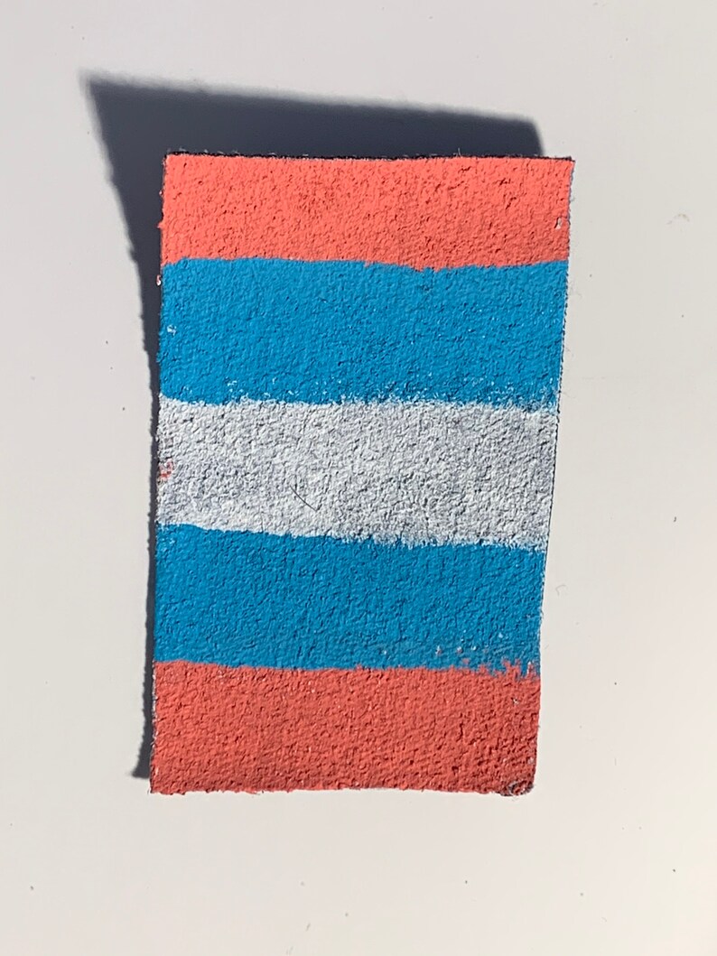 K&ouml;nnte beinhalten: Ein rechteckiges St&uuml;ck Stoff mit horizontalen Streifen in den Farben Rosa, Blau und Wei&szlig;.