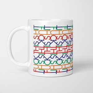 May include: White ceramic mug featuring the words "THIS SHIT" in a repeating pattern. The text is in a stylized font and uses green, orange, blue, and red colours. The mug has a white handle and is suitable for hot beverages.