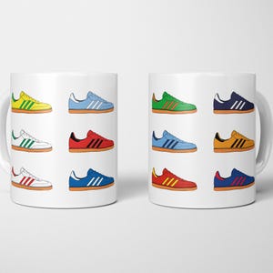 May include: A white ceramic mug featuring a repeating pattern of colorful sneakers. The sneakers are in various colors, including yellow, blue, red, green, and orange, each with contrasting stripes and a white sole.