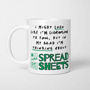 May include: White ceramic mug with a black and green text design. The text reads "I might look like I'm listening to you, but in my head I'm thinking about spreadsheets."