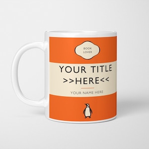May include: A white ceramic mug featuring a bright orange and cream-coloured design. The text reads BOOK LOVER, YOUR TITLE >>HERE<<, and YOUR NAME HERE. A small black and white penguin illustration is positioned at the bottom of the mug design.
