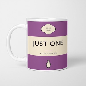 May include: White ceramic mug with a purple design. The mug features a penguin and the text "Book Lover", "Just One", and "More Chapter".